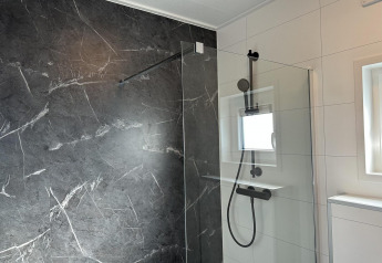 Doccia moderna con parete in marmo scuro e pannello in vetro al Zonneweelde Lodge Deluxe, Paesi Bassi.