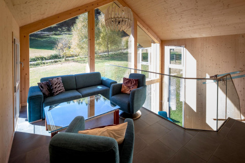 Zithoek met blauwe banken, glazen tafel en grote ramen bij Kreischberg Chalets 27, Oostenrijk.