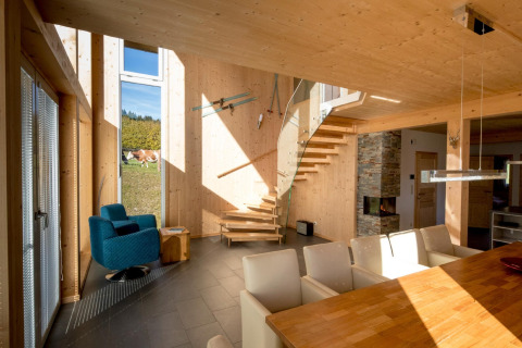 Modern interieur bij Kreischberg Chalets 27, Oostenrijk, met houtaccenten, wenteltrap en hoge ramen.