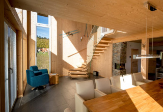 Modern interieur bij Kreischberg Chalets 27, Oostenrijk, met houtaccenten, wenteltrap en hoge ramen.
