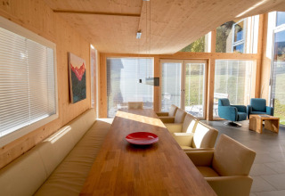 Moderne eethoek bij Kreischberg Chalets 27 in Oostenrijk met grote ramen, houten muren en comfortabele zitplaatsen