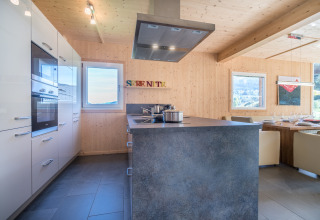 Moderne keuken en eetruimte bij Kreischberg Chalets 27 in Oostenrijk, met houten muren en uitzicht.