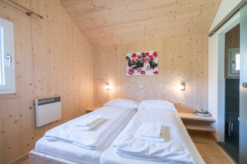 Lichte slaapkamer met twee eenpersoonsbedden, houten muren en kunstwerk in Kreischberg Chalets 27 in Oostenrijk.