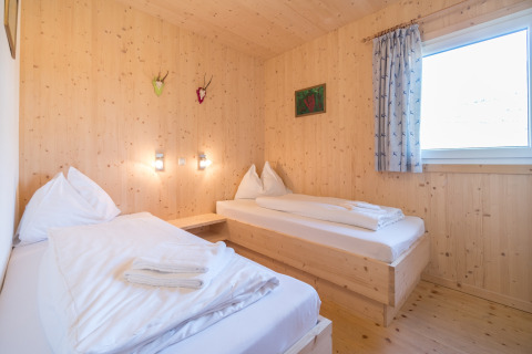 Houten kamer met twee eenpersoonsbedden en groot raam bij Kreischberg Chalets 27 in Oostenrijk.