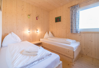 Houten kamer met twee eenpersoonsbedden en groot raam bij Kreischberg Chalets 27 in Oostenrijk.