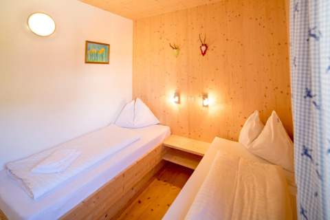Slaapkamer met twee eenpersoonsbedden, houten wanden en warme verlichting in Kreischberg Chalets 27, Oostenrijk.