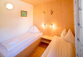 Slaapkamer met twee eenpersoonsbedden, houten wanden en warme verlichting in Kreischberg Chalets 27, Oostenrijk.