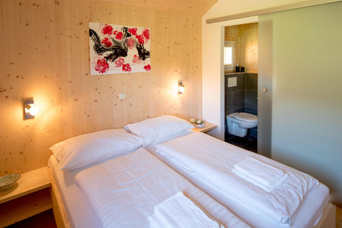 Knusse slaapkamer in Kreischberg Chalets 27 in Oostenrijk met tweepersoonsbed en eigen badkamer.