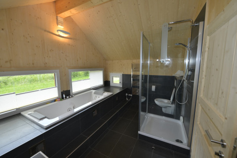 Moderne badkamer met groot bad, douche en houten wanden bij Kreischberg Chalets 27 in Oostenrijk.