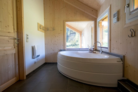 Lichte badkamer met hoekbad en grote ramen in Kreischberg Chalets 27, Oostenrijk, met uitzicht op het groen.