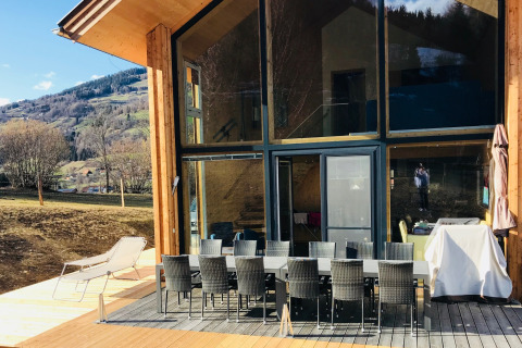 Zonnig terras bij Kreischberg Chalets 27 in Oostenrijk met eettafel, ligstoel en uitzicht op de bergen.