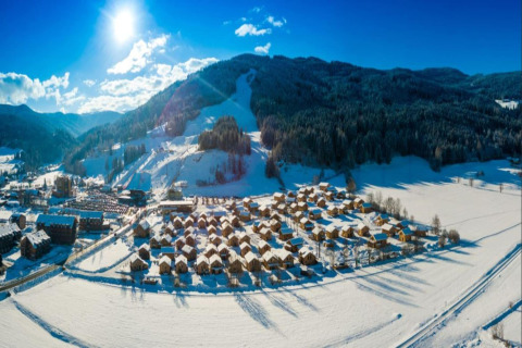 Luchtfoto van de besneeuwde 'Kreischberg Chalets 27' lodge in Oostenrijk, omringd door bergen.