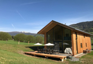 Modern houten lodge met ruim terras en bergzicht bij Kreischberg Chalets 27 in Oostenrijk, op een zonnige dag.