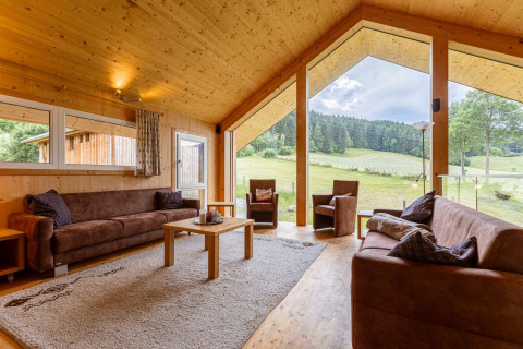 Wohnzimmer im Kreischberg Chalets 26 in Österreich mit großen Fenstern und Blick auf die Natur.