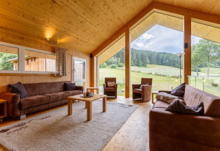 Wohnzimmer im Kreischberg Chalets 26 in Österreich mit großen Fenstern und Blick auf die Natur.