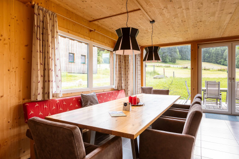 Heller Essbereich mit Holzwänden, großen Fenstern und Blick auf die Natur im Kreischberg Chalets 26 in Österreich.