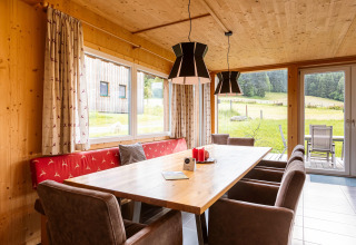 Heller Essbereich mit Holzwänden, großen Fenstern und Blick auf die Natur im Kreischberg Chalets 26 in Österreich.
