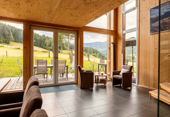 Moderne woonkamer met grote ramen, houten interieur en uitzicht op heuvels bij Kreischberg Chalets 26, Oostenrijk.