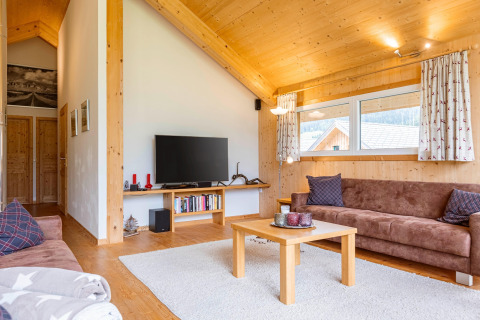 Wohnzimmer im Kreischberg Chalets 26 in Österreich mit braunen Sofas, Holzdecke und Fernseher.