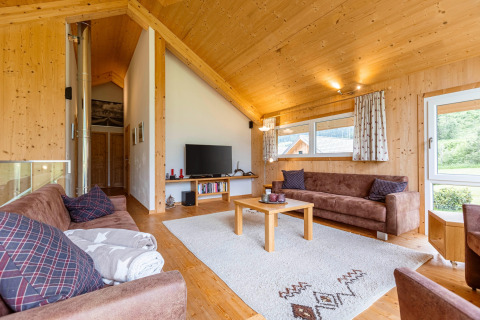 Wohnzimmer in der Kreischberg Chalets 26 Lodge in Österreich mit Holzwänden, Sofas und Teppich.