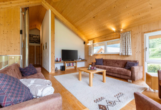 Wohnzimmer in der Kreischberg Chalets 26 Lodge in Österreich mit Holzwänden, Sofas und Teppich.