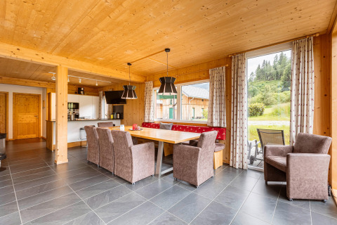 Helles Esszimmer aus Holz im Kreischberg Chalets 26, mit großem Fenster und Blick auf grüne Natur.