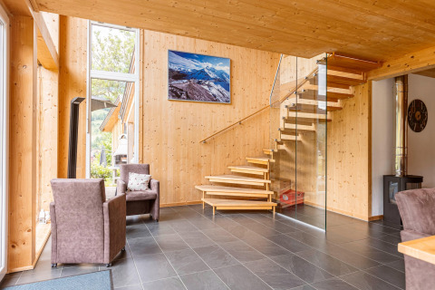 Modernes Interieur der Kreischberg Chalets 26 in Österreich mit Holz, Glas-Treppe und großen Fenstern.
