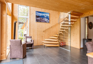 Modernes Interieur der Kreischberg Chalets 26 in Österreich mit Holz, Glas-Treppe und großen Fenstern.