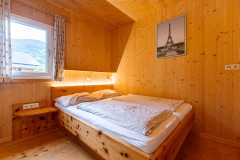Schlafzimmer im Kreischberg Chalets 26 in Österreich mit Holzwänden, Doppelbett und Fensterblick.