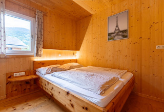 Schlafzimmer im Kreischberg Chalets 26 in Österreich mit Holzwänden, Doppelbett und Fensterblick.
