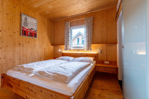 Schlafzimmer im Kreischberg Chalets 26, Österreich, mit Holzwänden, Doppelbett und natürlichem Licht.