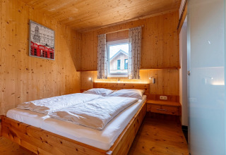 Schlafzimmer im Kreischberg Chalets 26, Österreich, mit Holzwänden, Doppelbett und natürlichem Licht.