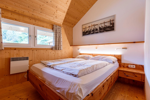 Schlafzimmer mit Holzbett und modernen Details in der Lodge Kreischberg Chalets 26 in Österreich.