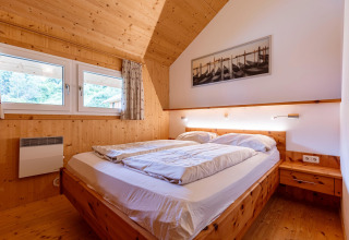 Schlafzimmer mit Holzbett und modernen Details in der Lodge Kreischberg Chalets 26 in Österreich.