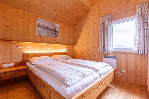 Schlafzimmer mit Holzwänden und Doppelbett in der Kreischberg Chalets 26 Lodge in Österreich, hell und gemütlich.