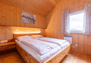 Schlafzimmer mit Holzwänden und Doppelbett in der Kreischberg Chalets 26 Lodge in Österreich, hell und gemütlich.