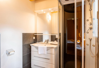 Modernes Badezimmer im Kreischberg Chalets 26 in Österreich mit Duschkabine, Waschtisch und Spiegel.