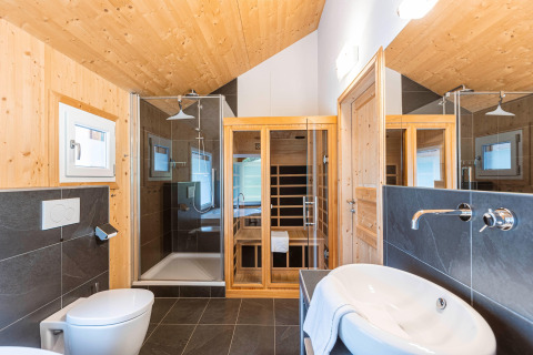 Modernes Badezimmer mit Holzverkleidung, Dusche, Sauna und Waschbecken im Kreischberg Chalets 26, Österreich.