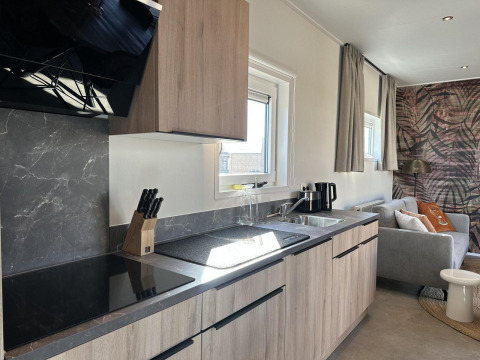 Moderne keuken en zithoek in Zonneweelde Lodge Deluxe op Camping Zonneweelde in Nederland, helder en huiselijk.
