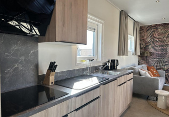 Cucina moderna e zona soggiorno alla Zonneweelde Lodge Deluxe presso Camping Zonneweelde, Paesi Bassi, luminosa e accogliente.