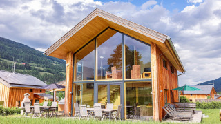 Voorzijde van Kreischberg Chalets 26 met grote glazen ramen, terrasmeubilair en bergachtige achtergrond.