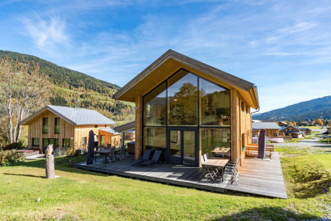 Moderne Holzchalets bei Kreischberg Chalets 26 in Österreich, mit großem Fenster und Berglandschaft im Hintergrund.