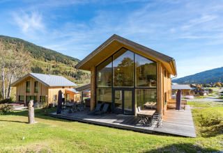 Moderne Holzchalets bei Kreischberg Chalets 26 in Österreich, mit großem Fenster und Berglandschaft im Hintergrund.