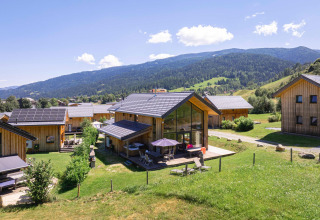Moderne Holzhütten der Kreischberg Chalets 26 in Österreich mit Bergen im Hintergrund an einem sonnigen Tag.