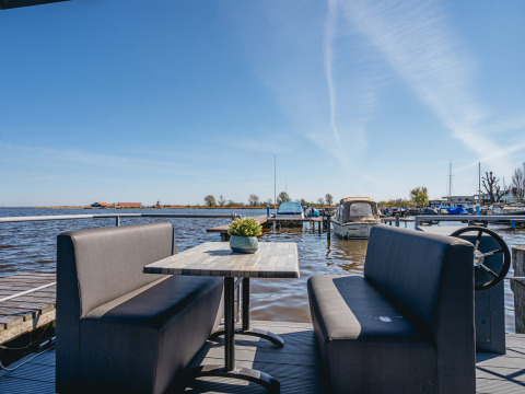 View from Houseboat «Havenlodge Plus» at Marina Uitgeest, Netherlands, with booth seating and boats docked.