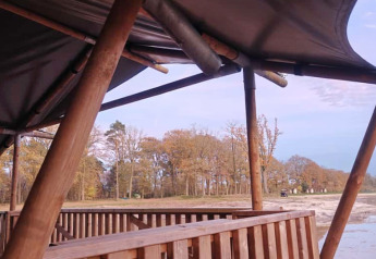 View from a safari tent with wooden terrace by the lake at Camping De Rammelbeek in the Netherlands.