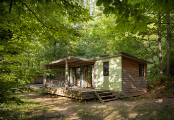 A cozy Mobile home Vancouver cabin sits nestled among lush green trees in a tranquil forest setting.