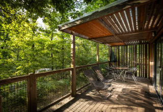 Terrasse en bois du Mobile home Vancouver à Huttopia Wattwiller, France, entourée par la forêt verdoyante.