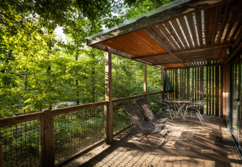Terrasse en bois du Mobile home Vancouver à Huttopia Wattwiller, France, entourée par la forêt verdoyante.