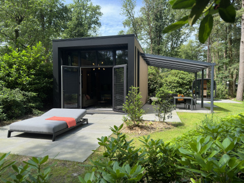 Moderne Veluwe Suite lodge met sauna, terras en ligbed, omgeven door groen en bossen in de natuur.